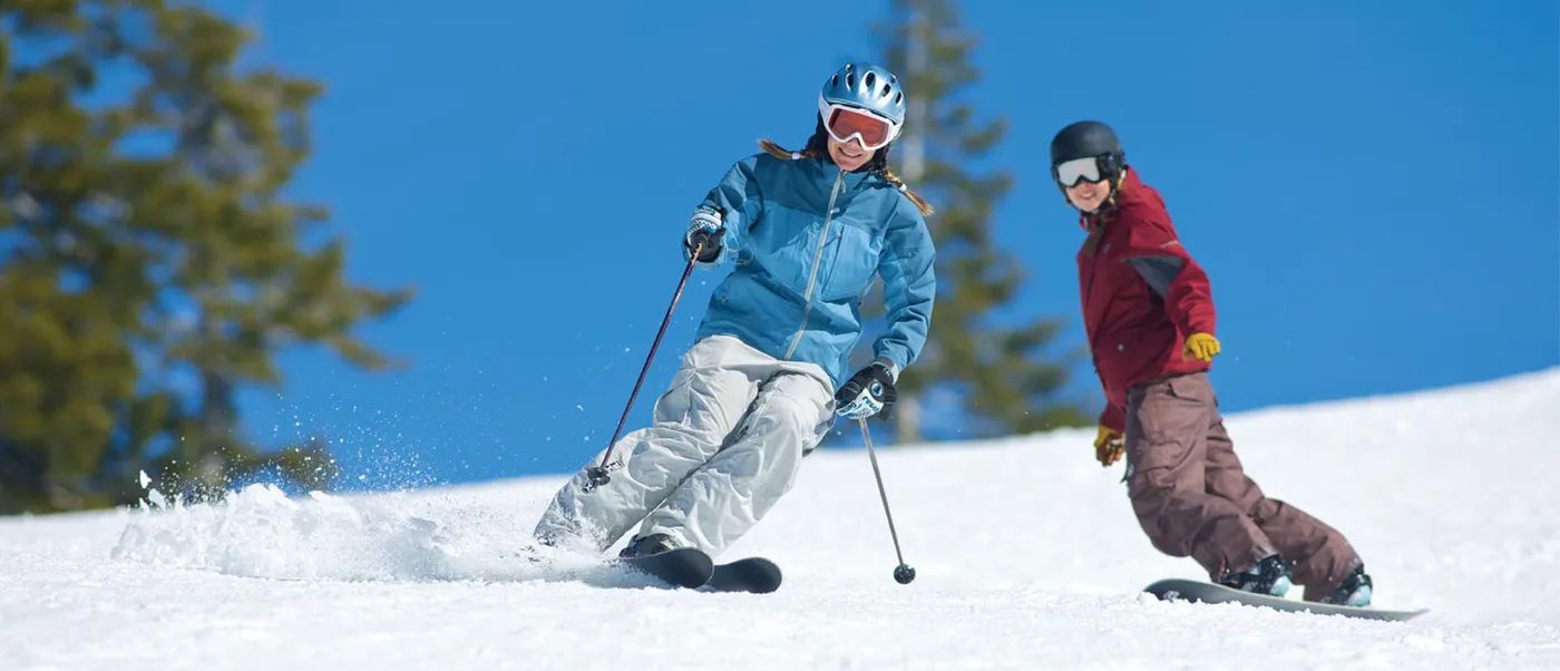 Skier and snowboarder descending a Gulmarg run